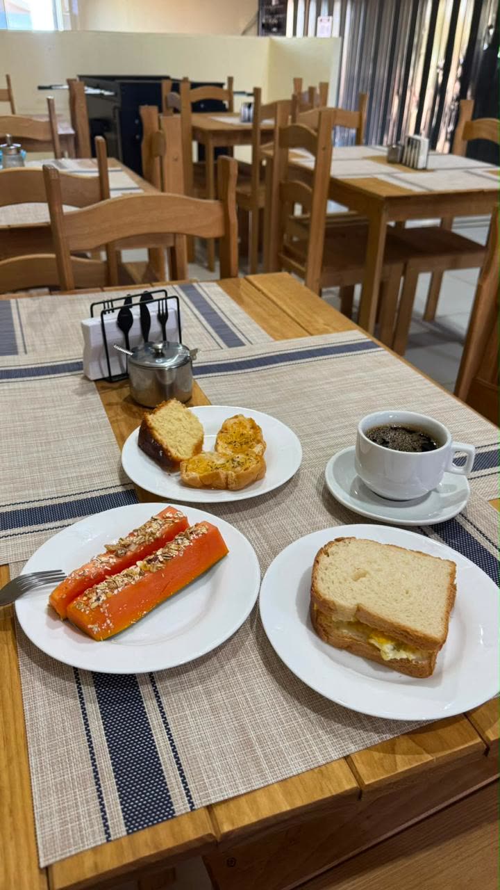 Prato servido no café da manhã com mamão, bolo, sanduíche e café