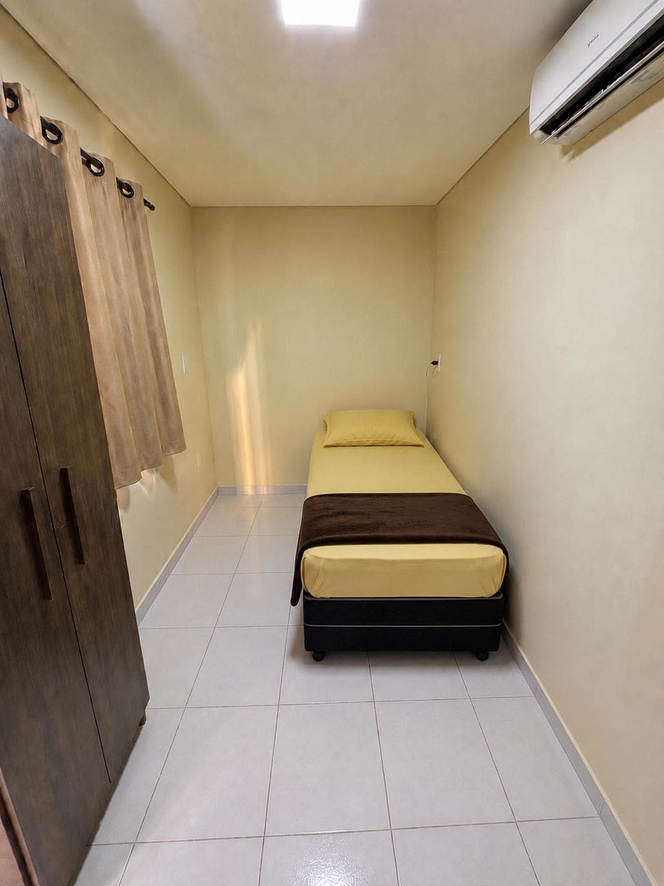 Quarto individual com cama de solteiro, guarda-roupa e ar-condicionado