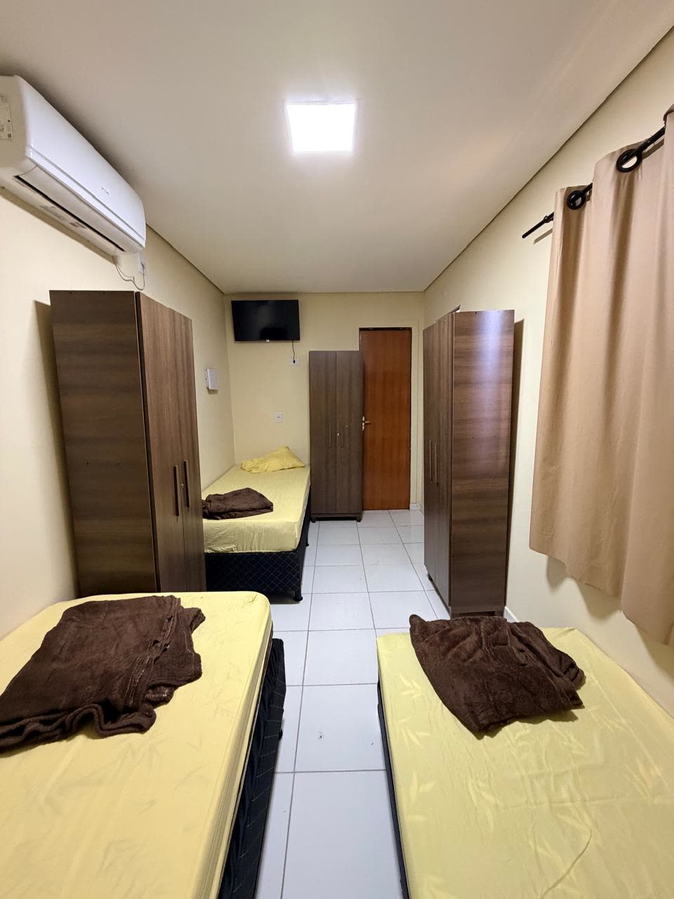 Quarto triplo com três camas de solteiro e dois guarda-roupas